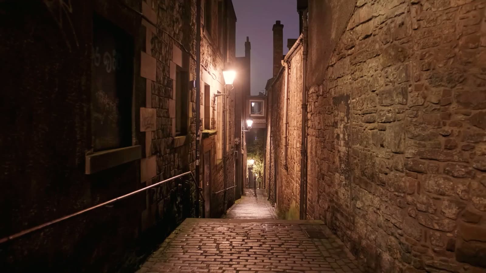 A narrow cobblestone alley in Barcelona's Gothic Quarter at night, warm lamplight reflecting off ancient stone walls on both sides, a covered stairway leading deeper into the maze