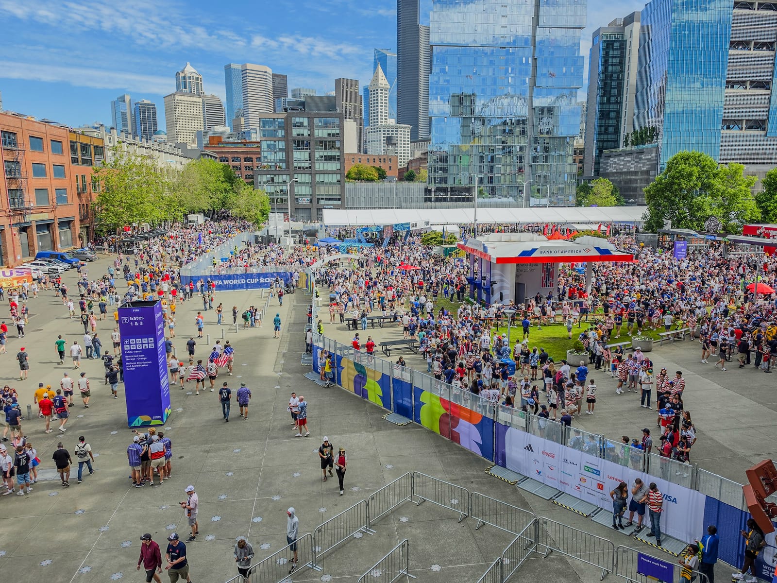 Crowds filling the plaza outside the stadium before a World Cup match in Seattle, with the downtown skyline in the background