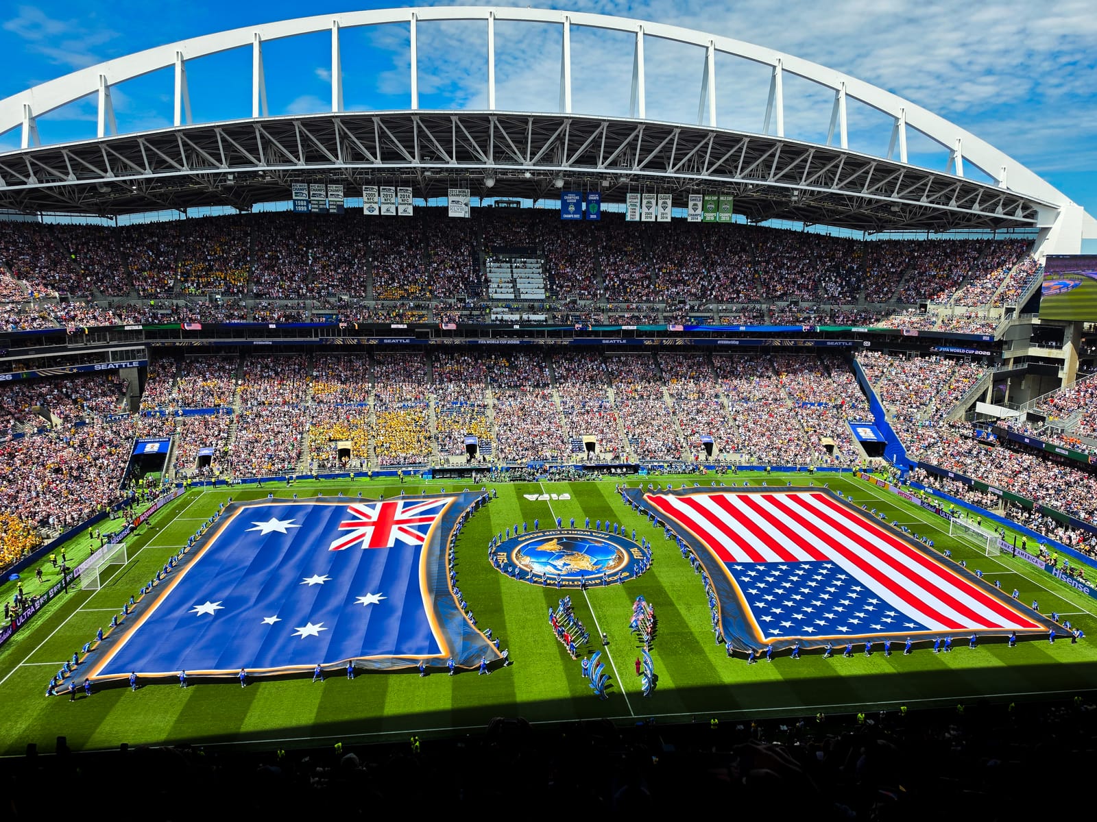 Packed Lumen Field in Seattle during the World Cup, with large Australia and United States flags spread across the pitch before a Team USA kickoff.